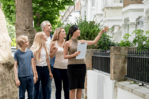 Working with a Realtor  Realtor pointing to a row home.  Looks like she is showing something to family with a teenage daughter and tween son