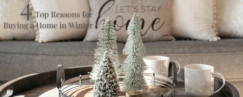 Header image for 4 top reasons for buying a home in winter. photo of a living room with a sofa with pillows and coffee table with winter center piece of evergreen trees, a candle and a mug