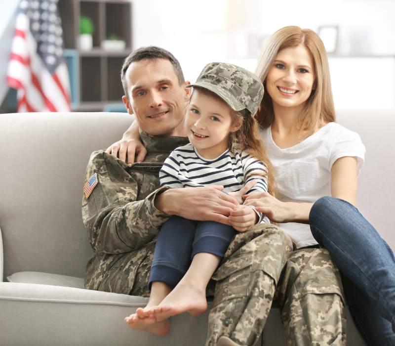 Young military family sitting on a couch dad is in fatigues daughter and wife