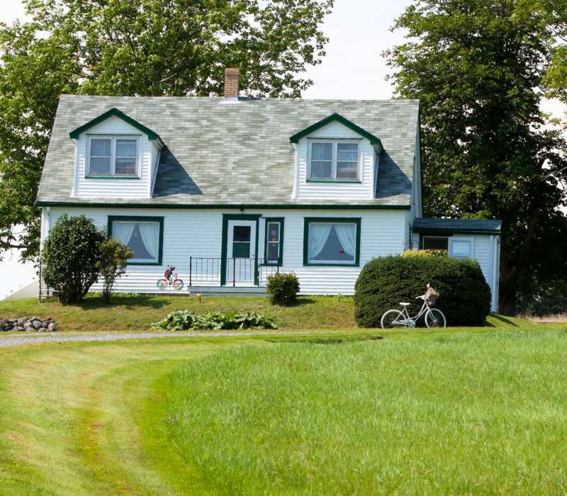 Image of a white country home with a gravel drive bike in the front yard