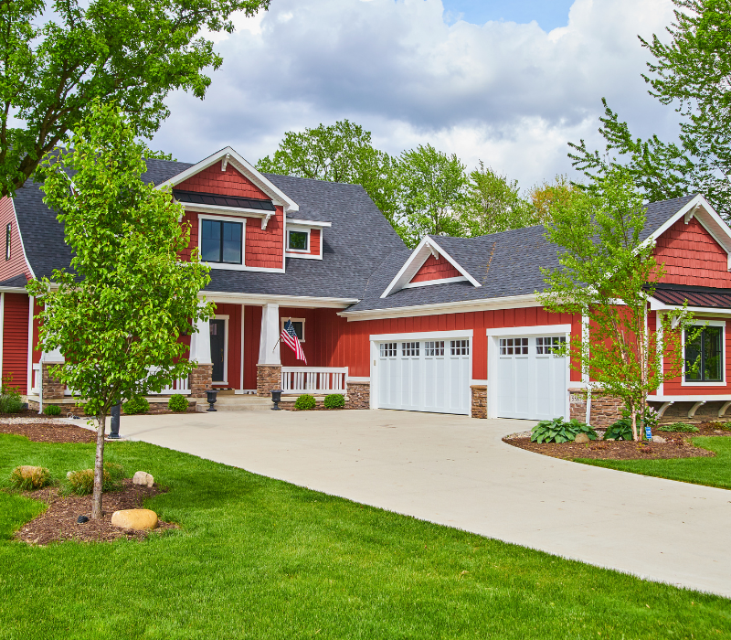 Photo of a two story red craftsman style home with 2 car garage